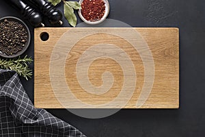 Kitchen cutting wooden board with spices and ingredients for cooking on black. Space for text. Top view