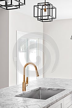 Kitchen detail shot with a gold faucet and modern lights.