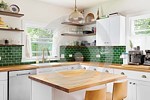 A kitchen detail with white cabinets, butcher block countertops, and green subway tiles.