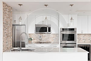 A kitchen detail with white cabinets and a stone and glass tile backsplash.