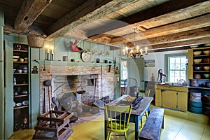 The kitchen, dining room and fireplace in a primitive colonial style home.