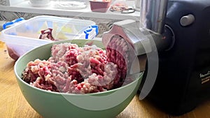 Kitchen electric meat grinder shreds meat into strips of minced meat. Unmodified camera color.