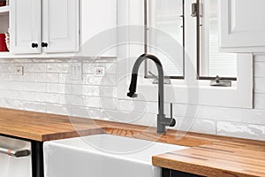 A kitchen faucet detail with a butcher block countertop and subway tile backsplash.