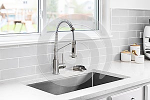 A kitchen faucet detail with a marble countertop and subway tile backsplash.