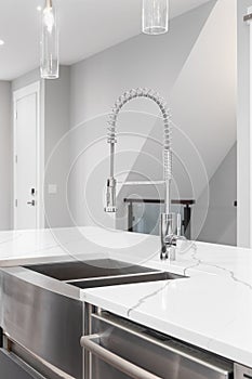 A kitchen faucet detail with a stainless steel apron sink.