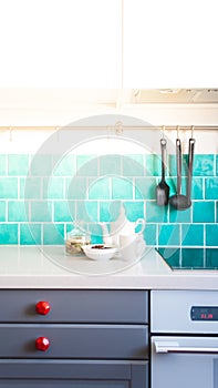 Kitchen features dark gray flat front cabinets paired with white quartz countertops and a glossy blue care tile.