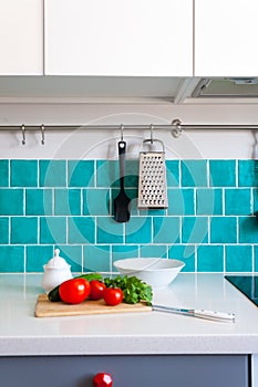 Kitchen features dark gray flat front cabinets paired with white quartz countertops and a glossy blue care tile.