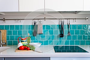 Kitchen features dark gray flat front cabinets paired with white quartz countertops and a glossy blue care tile.