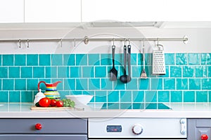 Kitchen features dark gray flat front cabinets paired with white quartz countertops and a glossy blue care tile.