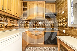 Kitchen front L-shaped fitted kitchen with Castilian-style wooden furniture, folding table on one side and striking vintage tiles