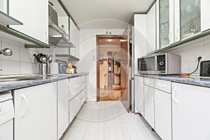 Kitchen furnished on both sides of the wall with white furniture