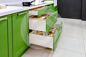 Kitchen furniture in green with open drawers