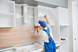 Kitchen installation. Worker assembling furniture