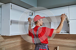 Kitchen installation. Worker assembling furniture