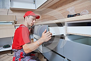 Kitchen installation. Worker assembling furniture