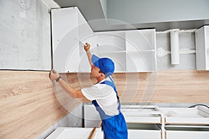 Kitchen installation. Worker assembling furniture