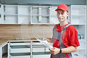 Kitchen installation. Worker assembling furniture