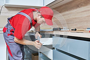 Kitchen installation. Worker assembling furniture