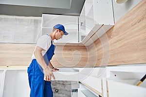 Kitchen installation. Worker assembling furniture