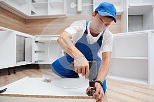 Kitchen installation. Worker assembling furniture