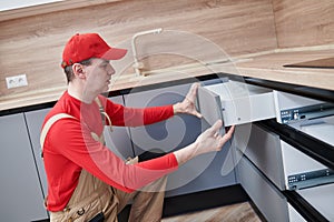 Kitchen installation. Worker assembling furniture