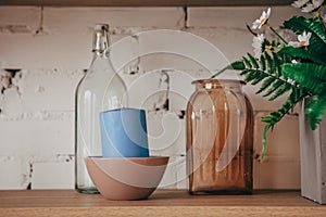 Kitchen interior: bottle, jar, candle and flowers in a vase on the shelf. Cozy home interior.