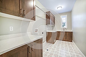 Kitchen interior with brown wooen cabinets white countertops sink and window
