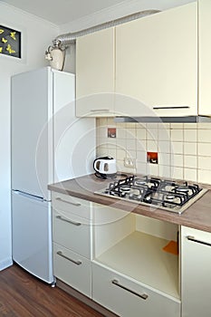 Kitchen interior fragment with gas stove and refrigerator