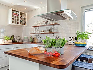 Kitchen interior with fresh basil and tomatoes and bread on the wooden kitchen counter-top