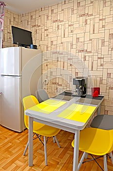 Kitchen interior with fridge and yellow chairs