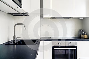 Kitchen interior. Modern white and black design. Scandinavian minimalist lifestyle. Induction cooker and stove, electric oven.