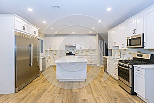 Kitchen with island sink cabinets, and hardwood floors in new luxury home three kitchen sinks