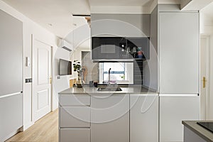 Kitchen island in vacation rental apartment with gray cabinets, silestone countertop, microwave and tv