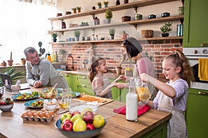 At the kitchen island very luminous in front of the camera beautiful and charismatic family all together have a healthy