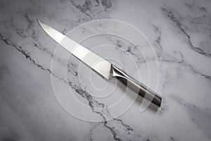 Kitchen knife made of steel on marble table. High angle view