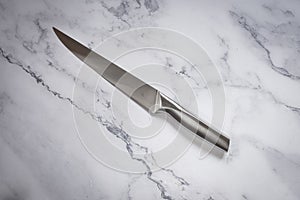 Kitchen knife made of steel on marble table. High angle view