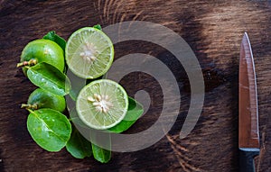 kitchen knife slice cut green lemon on wood cutting board.