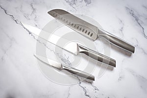 Kitchen knives set made of steel on marble table. High angle view