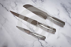 Kitchen knives set made of steel on marble table. High angle view