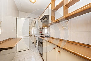 Kitchen with light-colored furniture with wooden ball handles to match the countertop and with cornices and moldings, electro-