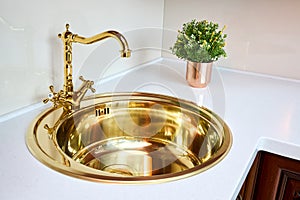 Kitchen luxurious interior with golden brass sink and faucet double tap mixer in contemporary modern design with stone