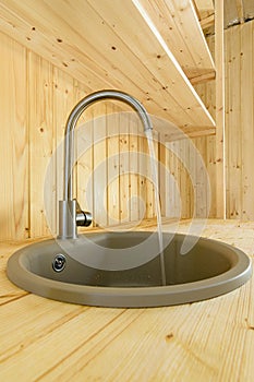 In a kitchen made of natural wood, water flows from the mixer