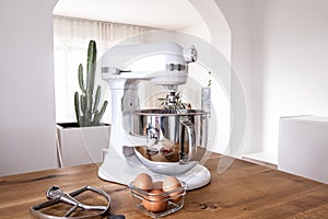 White kitchen machine and stand mixer on a wooden table in a bright design apartment photo