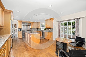 Kitchen with oak cabinets, oven, and breakfast table with chair in Encino, CA