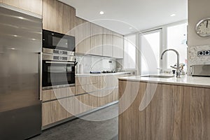 Kitchen with oak furniture, integrated appliances, white stone