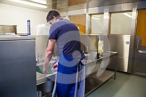 Kitchen porter washing up at sink