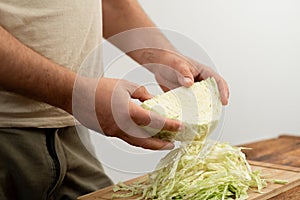 Kitchen preparation of cabbage, hands at work on a chopping board.