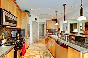 Kitchen room with brown cabinets, stainless steel, granite counter top.