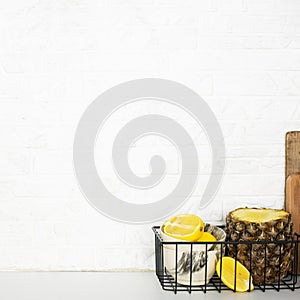 Kitchen shelf with baskets for storing products, pineapple, lemons, cutlery in a glass, chopping wooden boards on a