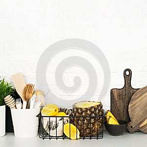 Kitchen shelf with baskets for storing products, pineapple, lemons, cutlery in a glass, chopping wooden boards on a